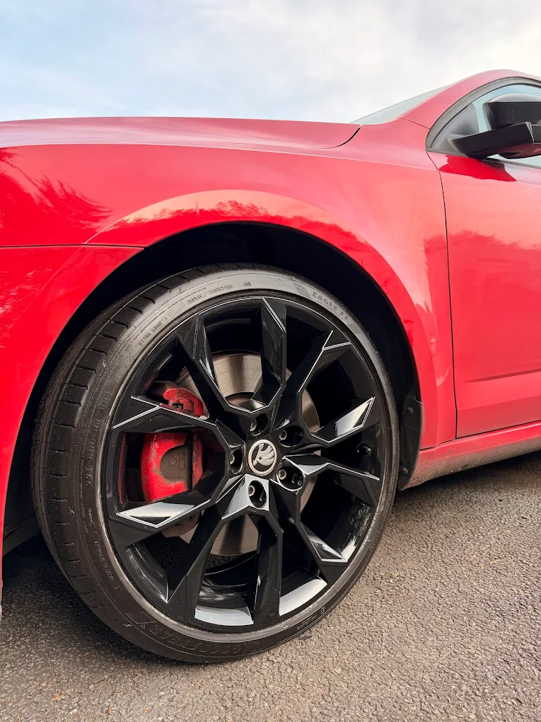 Black alloy wheel fitted to a red car